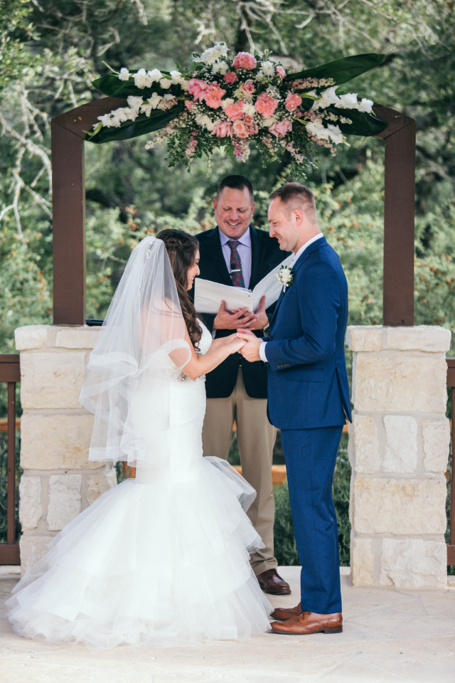 Bride and groom looking at one another, holding hands as Rev Reid Wilson with Texas Wedding Ministers officiates their wedding