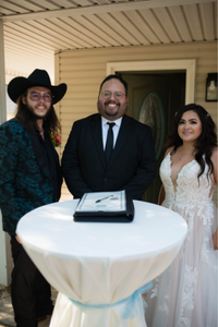 Pastor Isa Torres, with Texas Wedding Ministers, smiling with a couple after signing their marriage license.