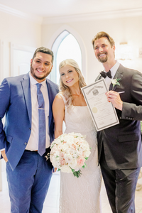 Pastor Alvaro Josue Cassio, an officiant with Texas Wedding Minister, with a couple at Ashton Gardens wedding venue. Pastor Alvaro Josue Cassio, with Texas Wedding Minister, smiling with a couple while they hold their wedding license at Ashton Gardens wedding venue.